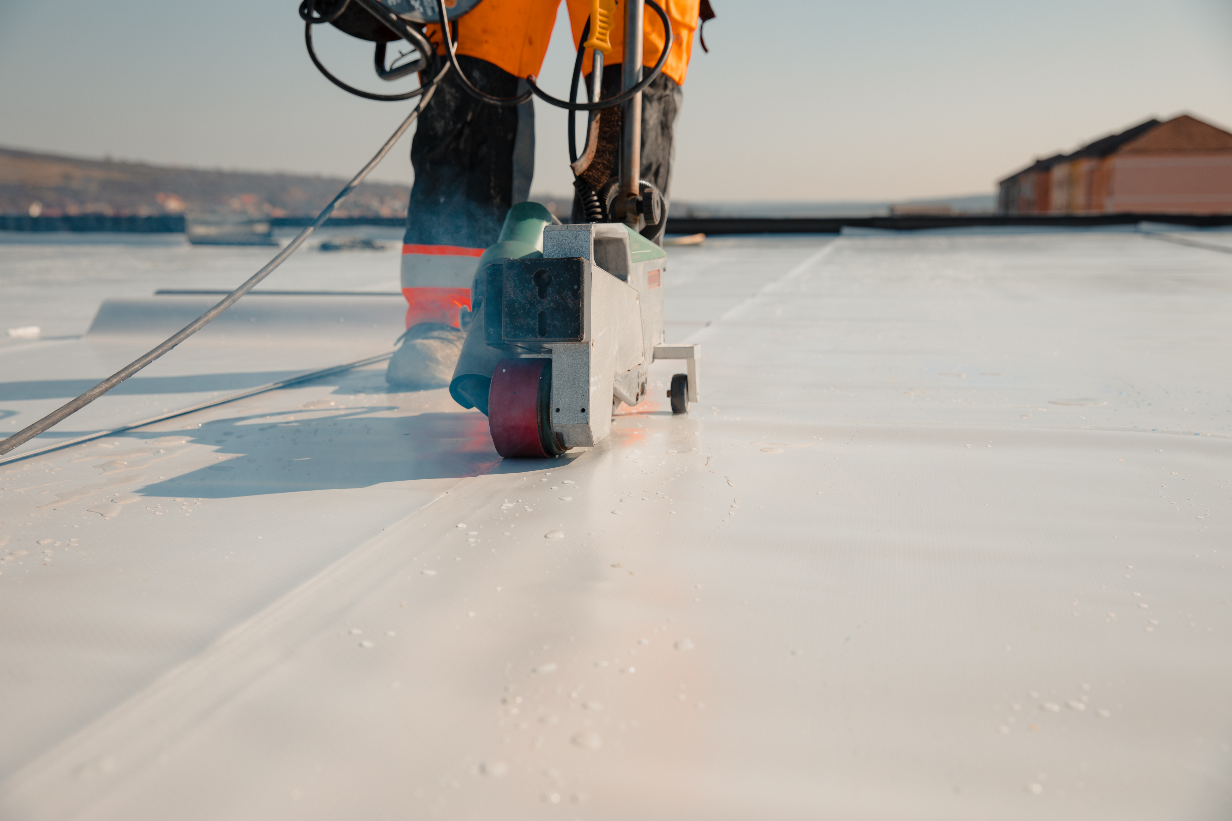 Roofing material being installed with a roller